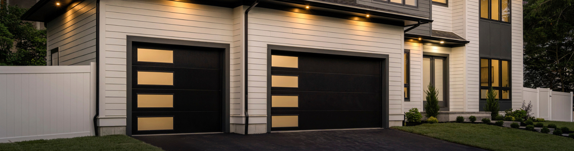 two black modern garage doors with windows down the side glowing